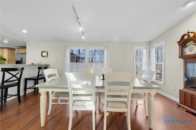 dining area with rail lighting, dark wood-type flooring, and baseboards