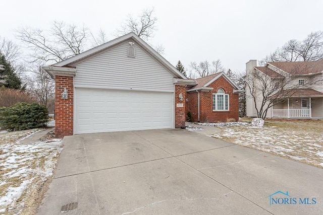 view of front of property with a chimney, brick siding, an attached garage, and driveway