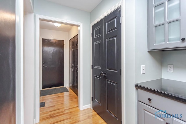 hall with visible vents, light wood-type flooring, and baseboards