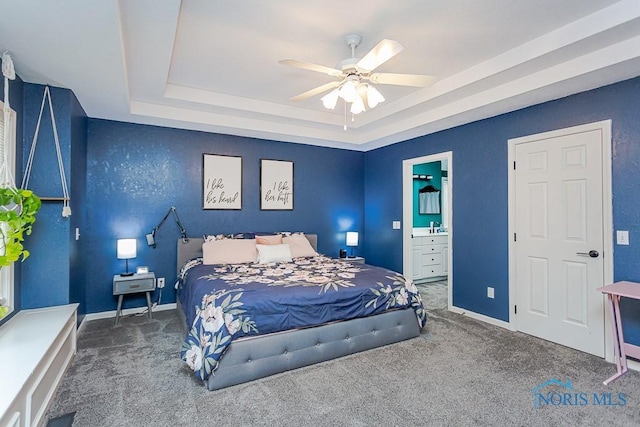 carpeted bedroom with ceiling fan, ensuite bathroom, a raised ceiling, and baseboards