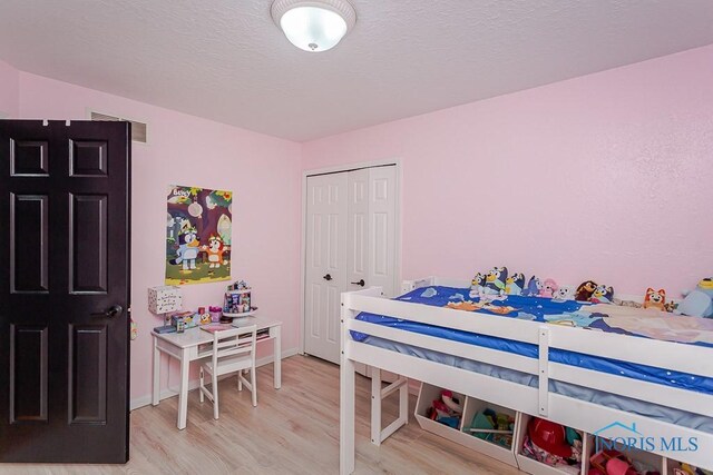 bedroom featuring a closet, visible vents, light wood-style flooring, and a textured ceiling