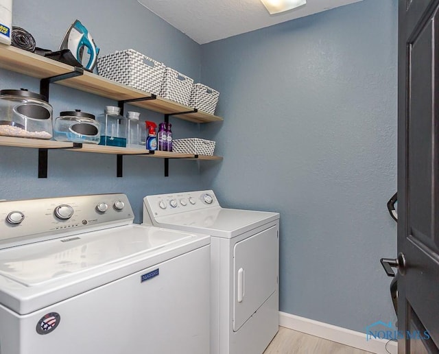 clothes washing area featuring washer and clothes dryer, light wood finished floors, laundry area, and baseboards
