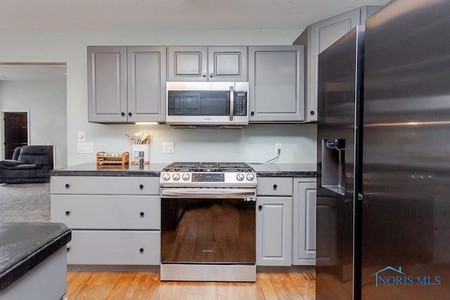 kitchen featuring dark countertops, appliances with stainless steel finishes, light wood-style flooring, and gray cabinets