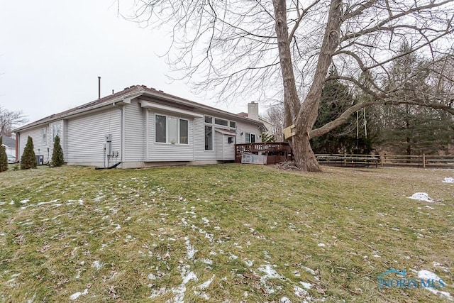 view of property exterior featuring a deck, a yard, fence, and a chimney