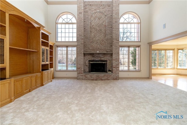 unfurnished living room with carpet flooring, plenty of natural light, and a brick fireplace