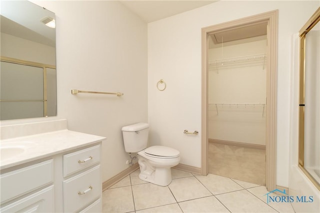 bathroom with vanity, tile patterned flooring, a spacious closet, an enclosed shower, and toilet