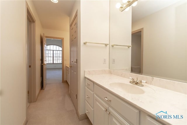 bathroom with toilet, vanity, and baseboards