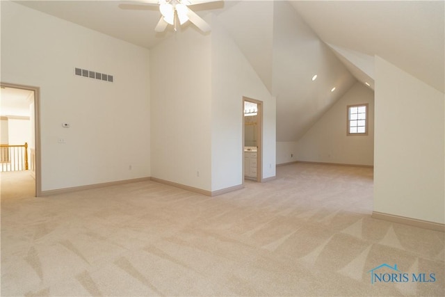 additional living space with visible vents, baseboards, light colored carpet, ceiling fan, and vaulted ceiling