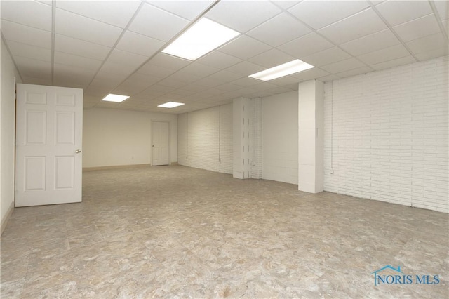 spare room with a drop ceiling and brick wall