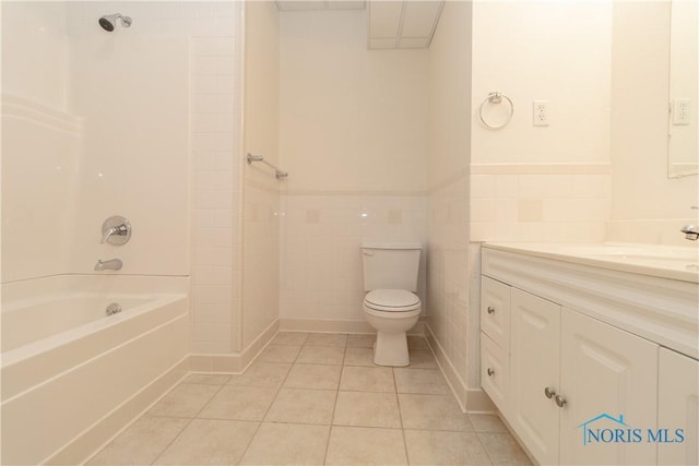 bathroom featuring a wainscoted wall, toilet, tile walls, tile patterned flooring, and vanity