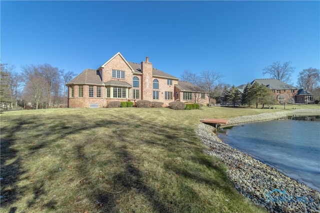 view of front of property featuring a front lawn, a water view, and a chimney