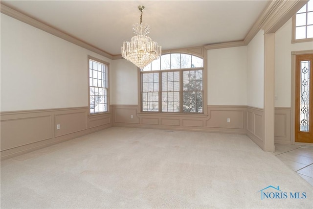 unfurnished dining area with a notable chandelier, ornamental molding, carpet, and a wainscoted wall