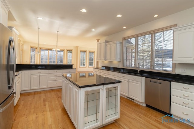 kitchen with a sink, stainless steel appliances, light wood-type flooring, and white cabinets