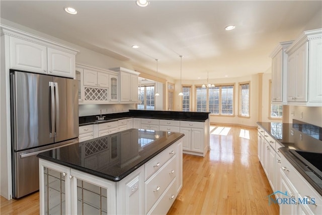 kitchen featuring plenty of natural light, a peninsula, light wood-type flooring, and freestanding refrigerator