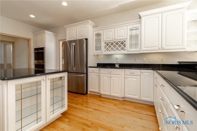 kitchen featuring light wood-style flooring, recessed lighting, white cabinets, glass insert cabinets, and appliances with stainless steel finishes