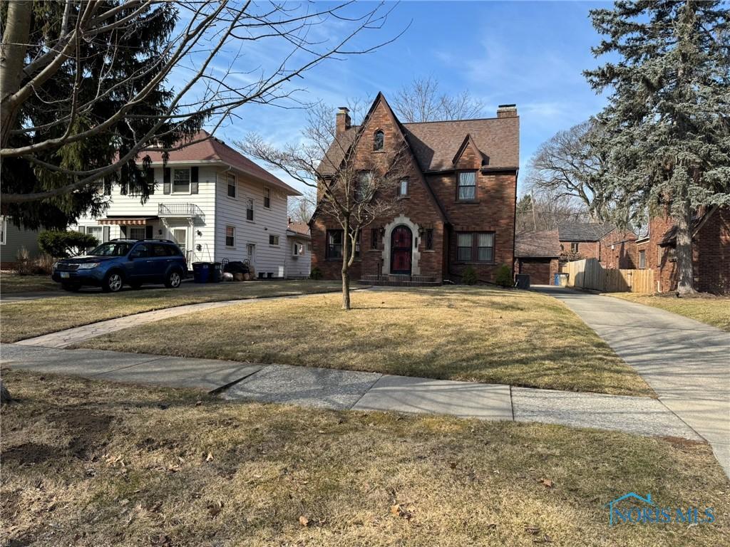 view of front of house with fence, concrete driveway, a front yard, a garage, and a chimney