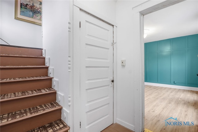 stairs with a decorative wall and wood finished floors