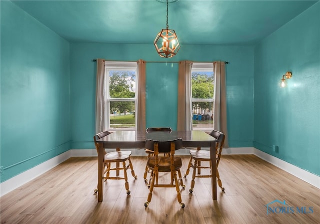 dining space with a notable chandelier, wood finished floors, and baseboards