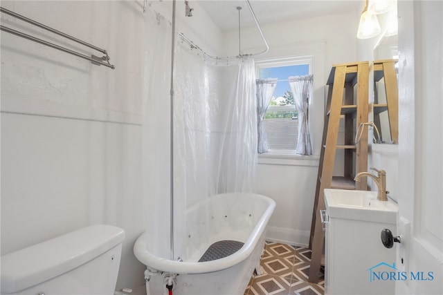 full bath featuring vanity, a freestanding tub, toilet, and baseboards