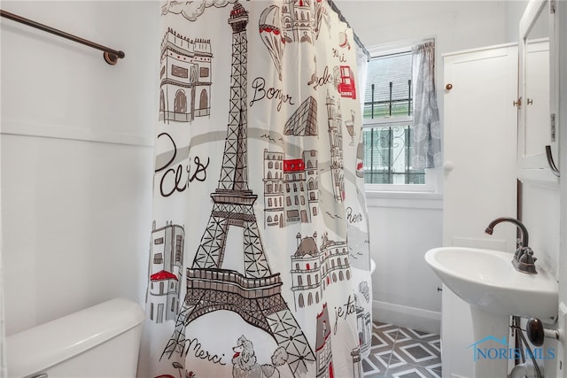 bathroom with curtained shower, toilet, and baseboards