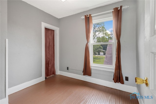 spare room featuring baseboards, plenty of natural light, and hardwood / wood-style flooring