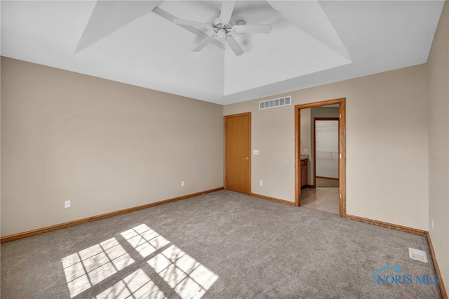 unfurnished bedroom featuring visible vents, light carpet, and a raised ceiling