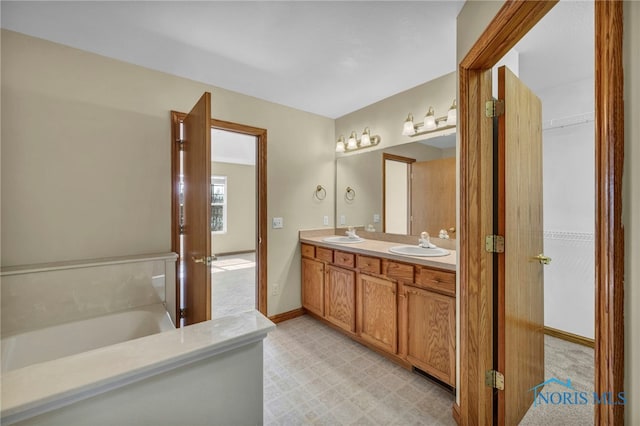 bathroom featuring a sink, baseboards, double vanity, and tile patterned floors