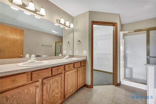 full bathroom featuring a walk in closet, a shower stall, double vanity, and a sink