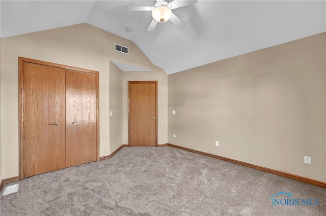 unfurnished bedroom with visible vents, carpet, lofted ceiling, a closet, and a ceiling fan