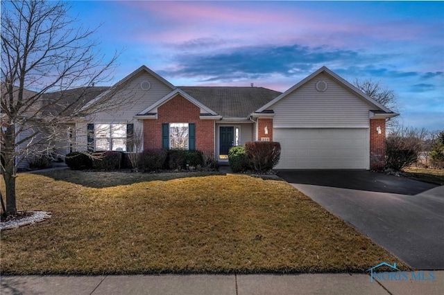 single story home with a yard, brick siding, a garage, and driveway