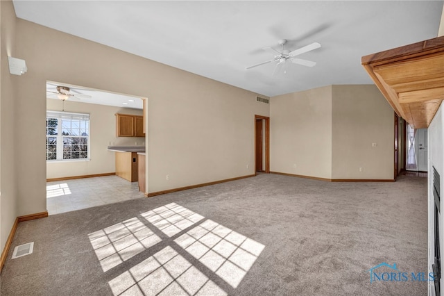 unfurnished living room featuring visible vents, light colored carpet, baseboards, and a ceiling fan