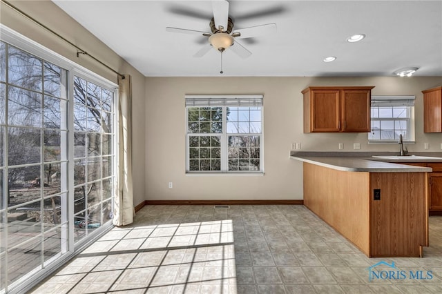 kitchen featuring brown cabinets, a ceiling fan, recessed lighting, a peninsula, and baseboards