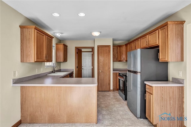 kitchen with recessed lighting, a peninsula, freestanding refrigerator, electric range, and a sink