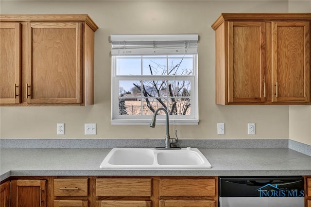 kitchen with brown cabinetry, dishwashing machine, light countertops, and a sink