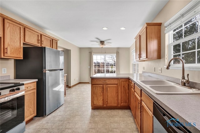 kitchen featuring a sink, appliances with stainless steel finishes, a peninsula, light countertops, and ceiling fan