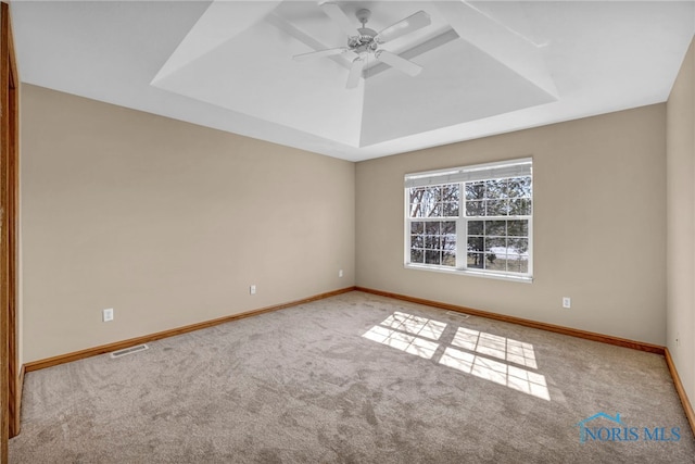 spare room featuring visible vents, a raised ceiling, baseboards, and carpet floors