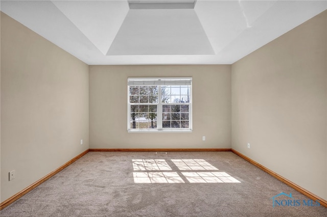 carpeted empty room featuring baseboards, a raised ceiling, and visible vents