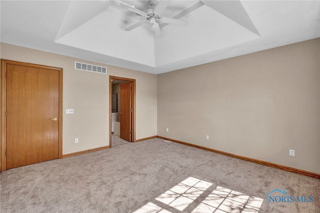 unfurnished bedroom featuring a raised ceiling, carpet, visible vents, and baseboards