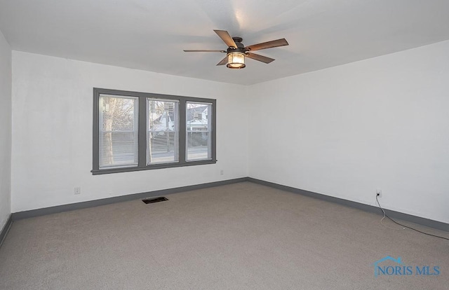 empty room featuring visible vents, carpet flooring, baseboards, and a ceiling fan