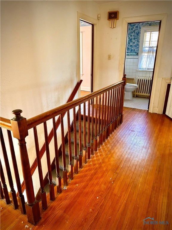 staircase with radiator heating unit and hardwood / wood-style flooring