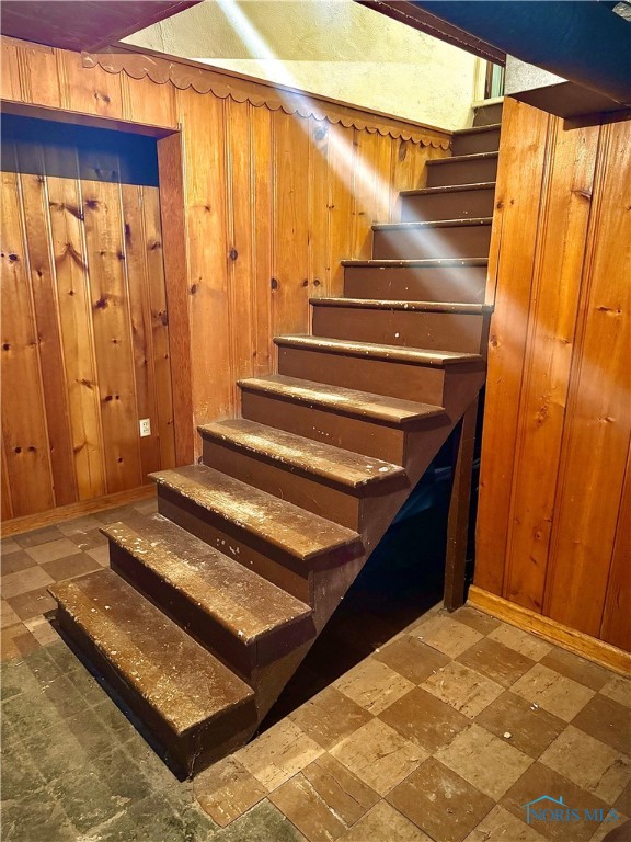 stairs with tile patterned floors and wooden walls