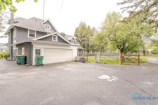 121 Eagle Point Dr, Rossford, OH 43460 - view of home's exterior with fence, a garage, a chimney, asphalt driveway, and central air condition unit