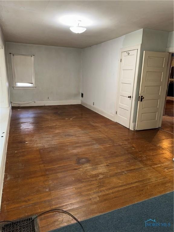 unfurnished room with dark wood finished floors and baseboards