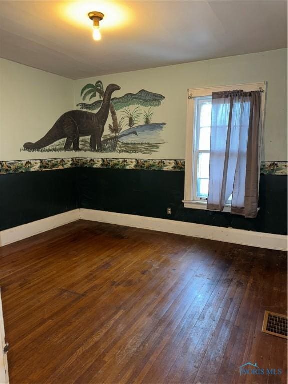 spare room featuring visible vents, baseboards, and hardwood / wood-style flooring