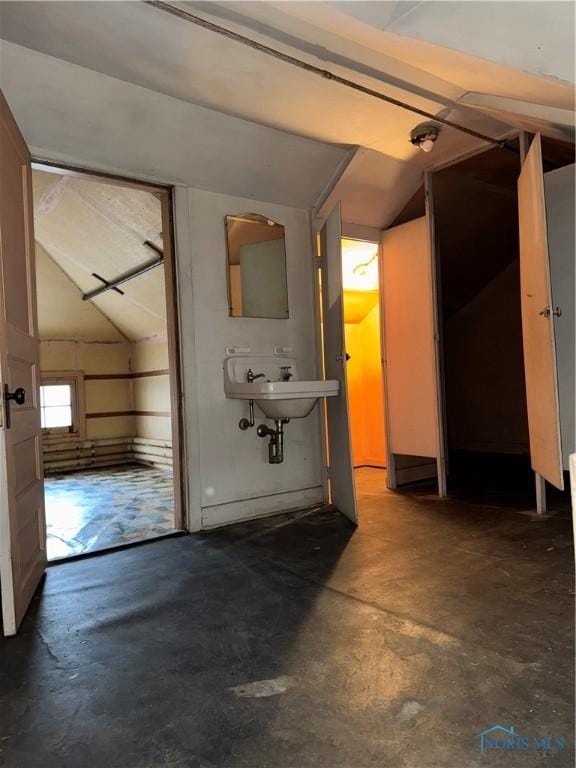 bathroom featuring concrete floors, lofted ceiling, and a sink