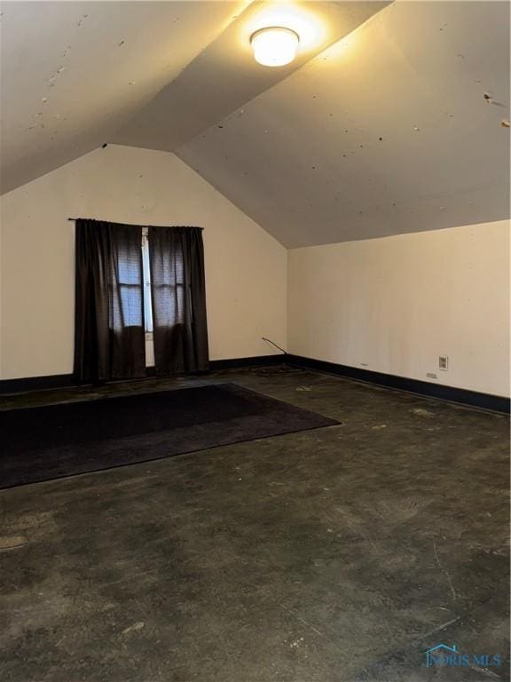 additional living space with baseboards and vaulted ceiling