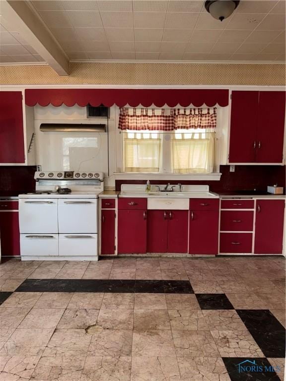 kitchen with a sink, double oven range, red cabinets, and yellow cabinets