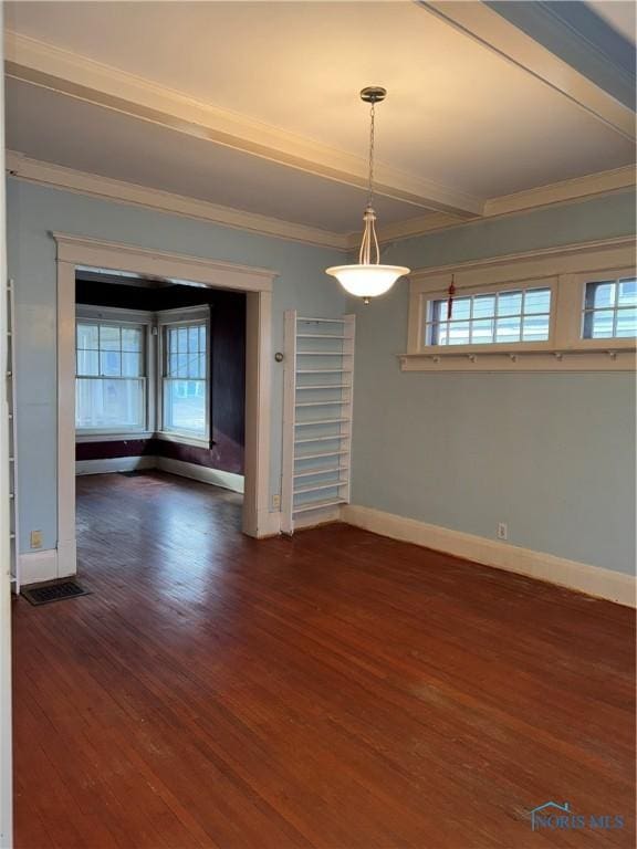 unfurnished room with dark wood-style floors, visible vents, baseboards, and ornamental molding