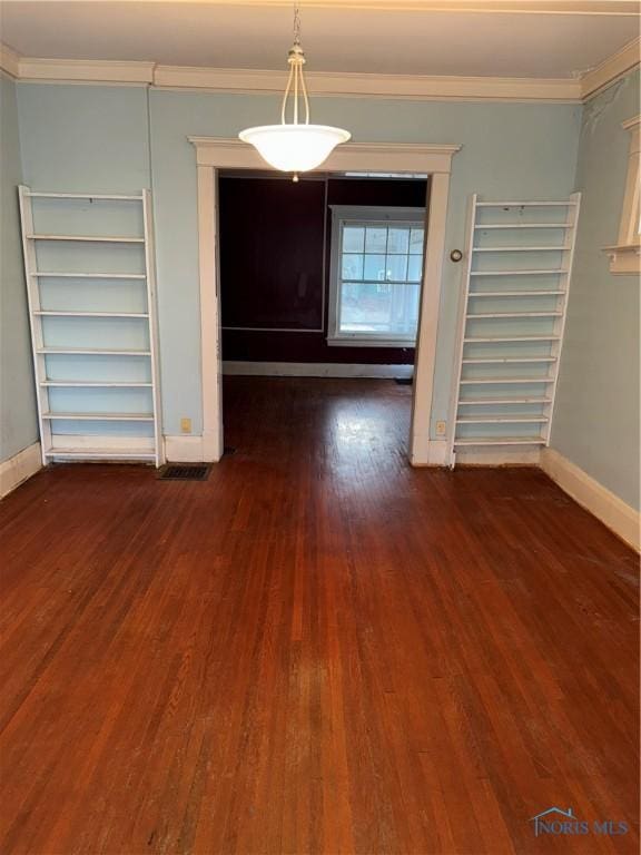 unfurnished dining area with dark wood finished floors, baseboards, and ornamental molding