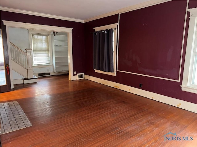 unfurnished room featuring visible vents, stairs, crown molding, and wood finished floors